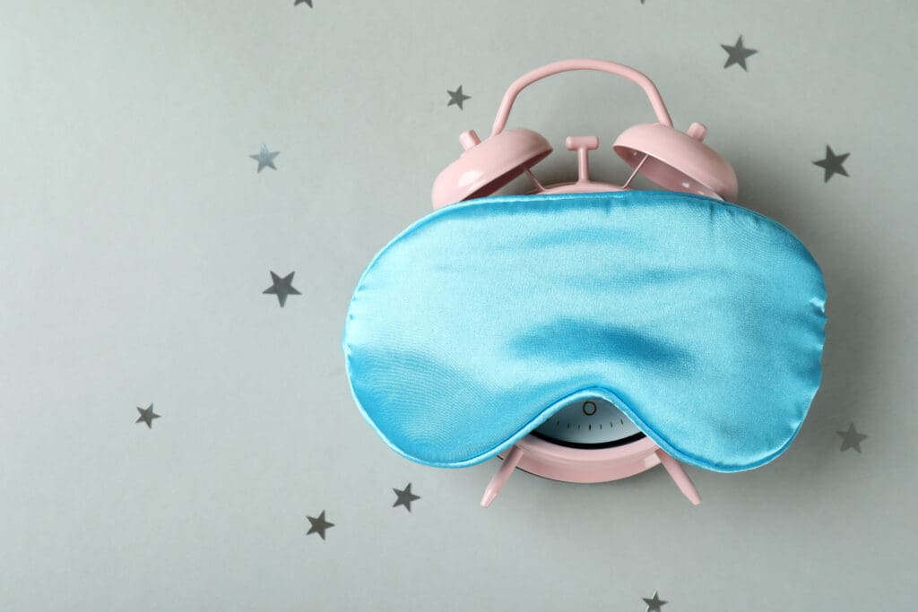 Alarm clock with sleep mask on gray background