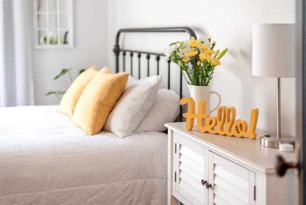 Cheerful yellow hello sign and fresh flowers in a clean and bright bedroom