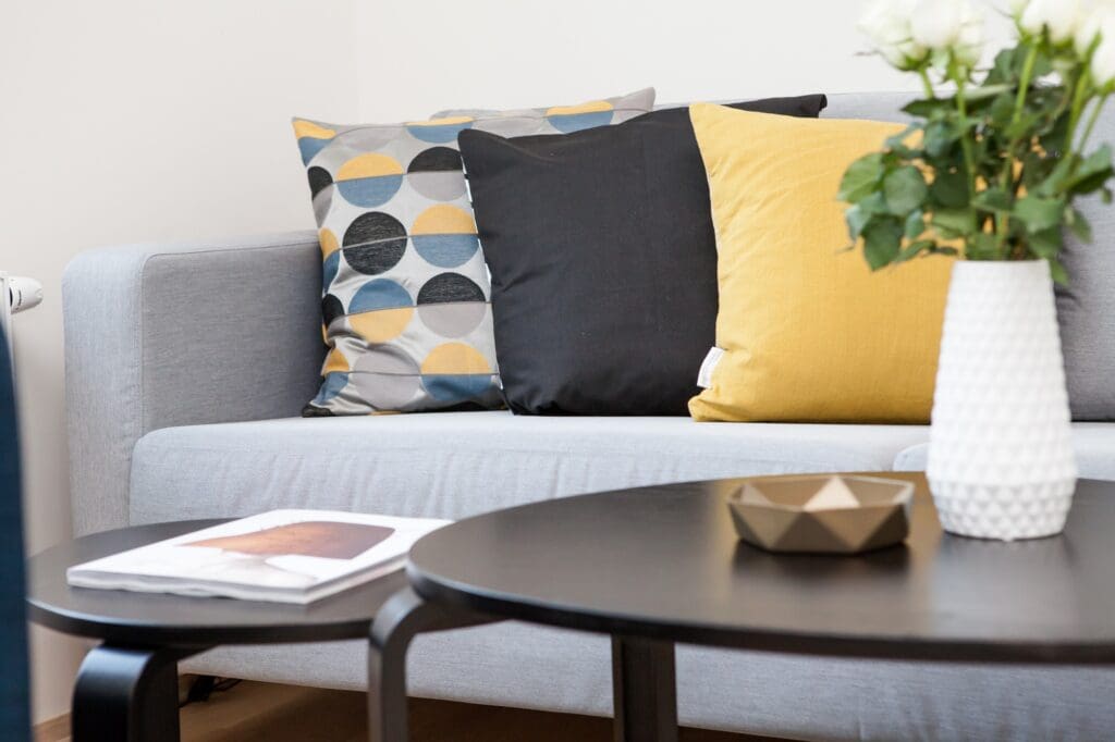 Neutral color and furniture in living room with colorful decorative pillows in yellow and blue.  