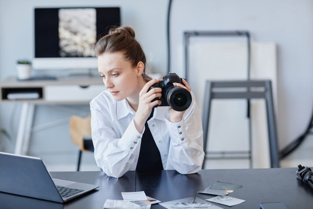 Portrait of young female photographer using laptop and photo camera.  Concept of photo editing