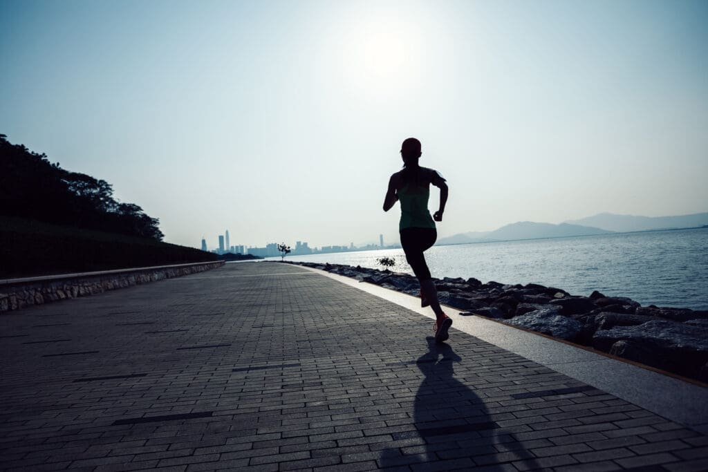 sporty young fitness woman running on sunrise coast trail