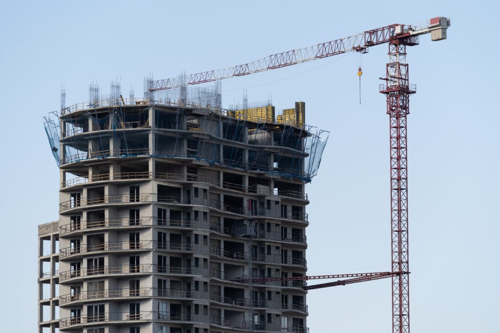 Multi-story residential building with tower crane with no construction taking place  Concept of limited building construction. 