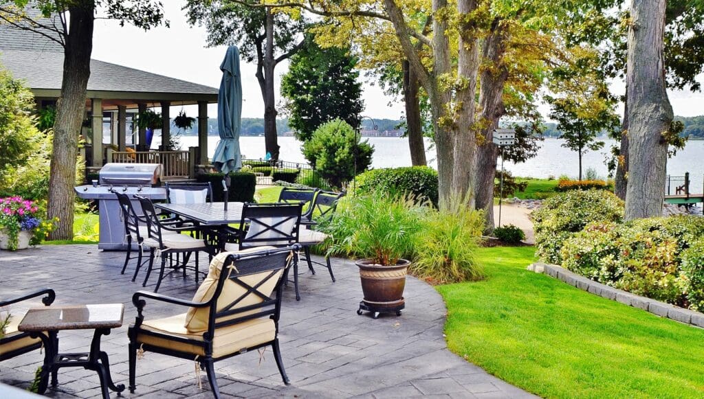 Outdoor living space with chairs, a grill and plants, paved patio