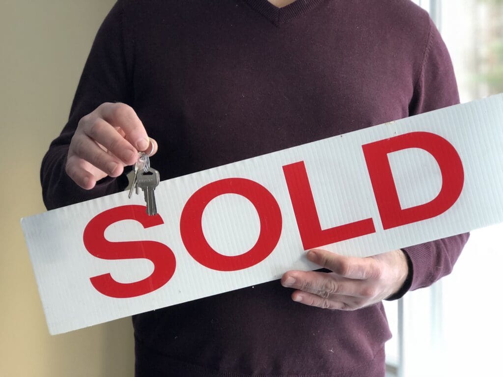 Man holding Sold Sign and keys to a home.