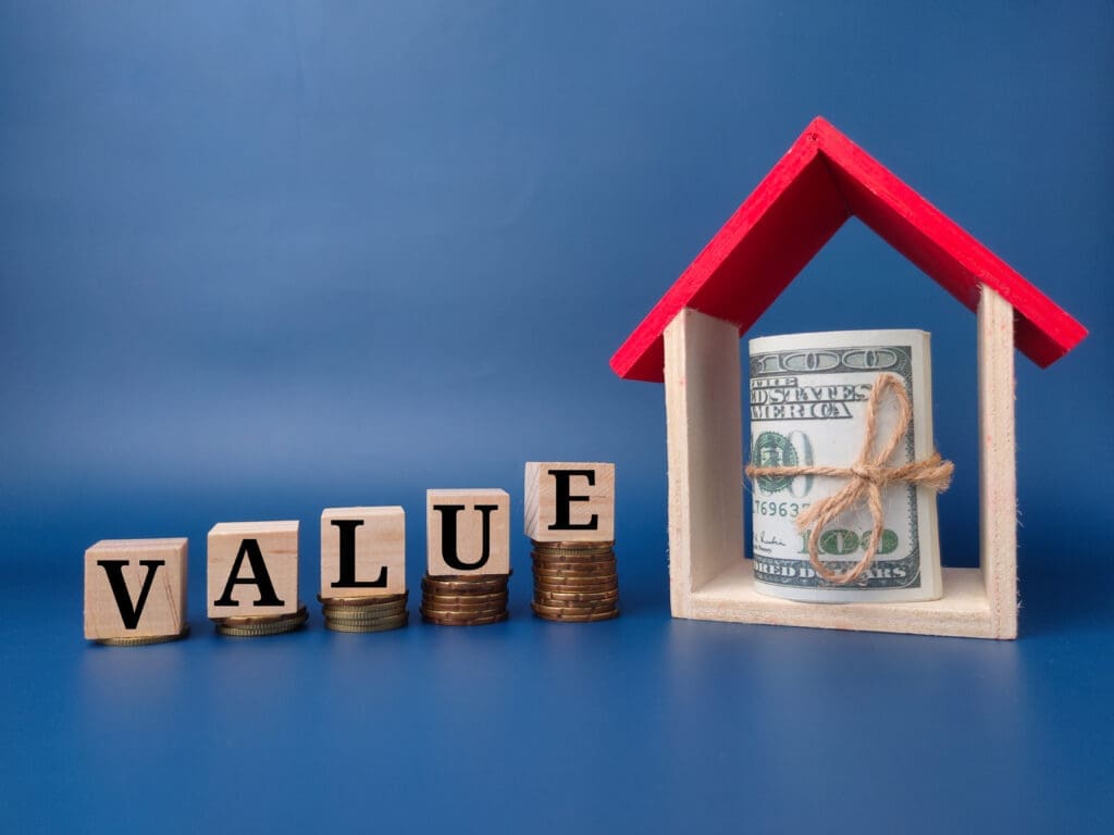 Homeownership remains a high-priority goal. Toy house and banknote with the word VALUE on a blue background.