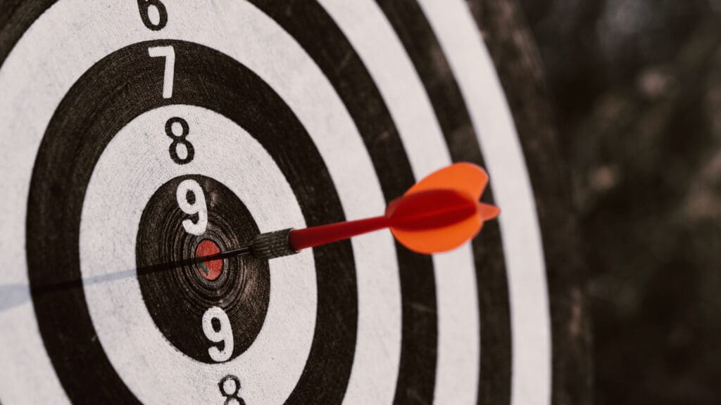 Close up red dart arrow hitting target center dartboard 