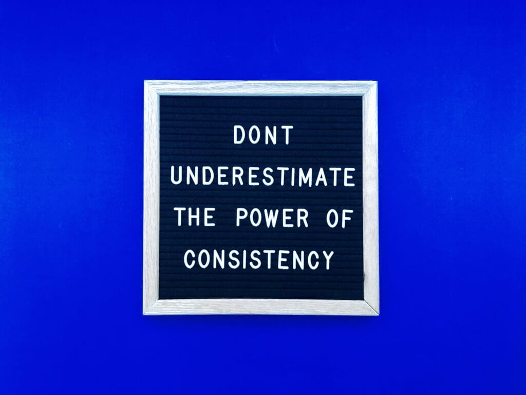 Sign with Don't Underestimate the Power of Consistency.  Concept of consistency in social media marketing