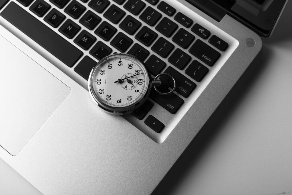 silver laptop with stopwatch on he keyboard closeup